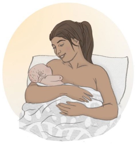 Mother sitting in bed breastfeesing her baby