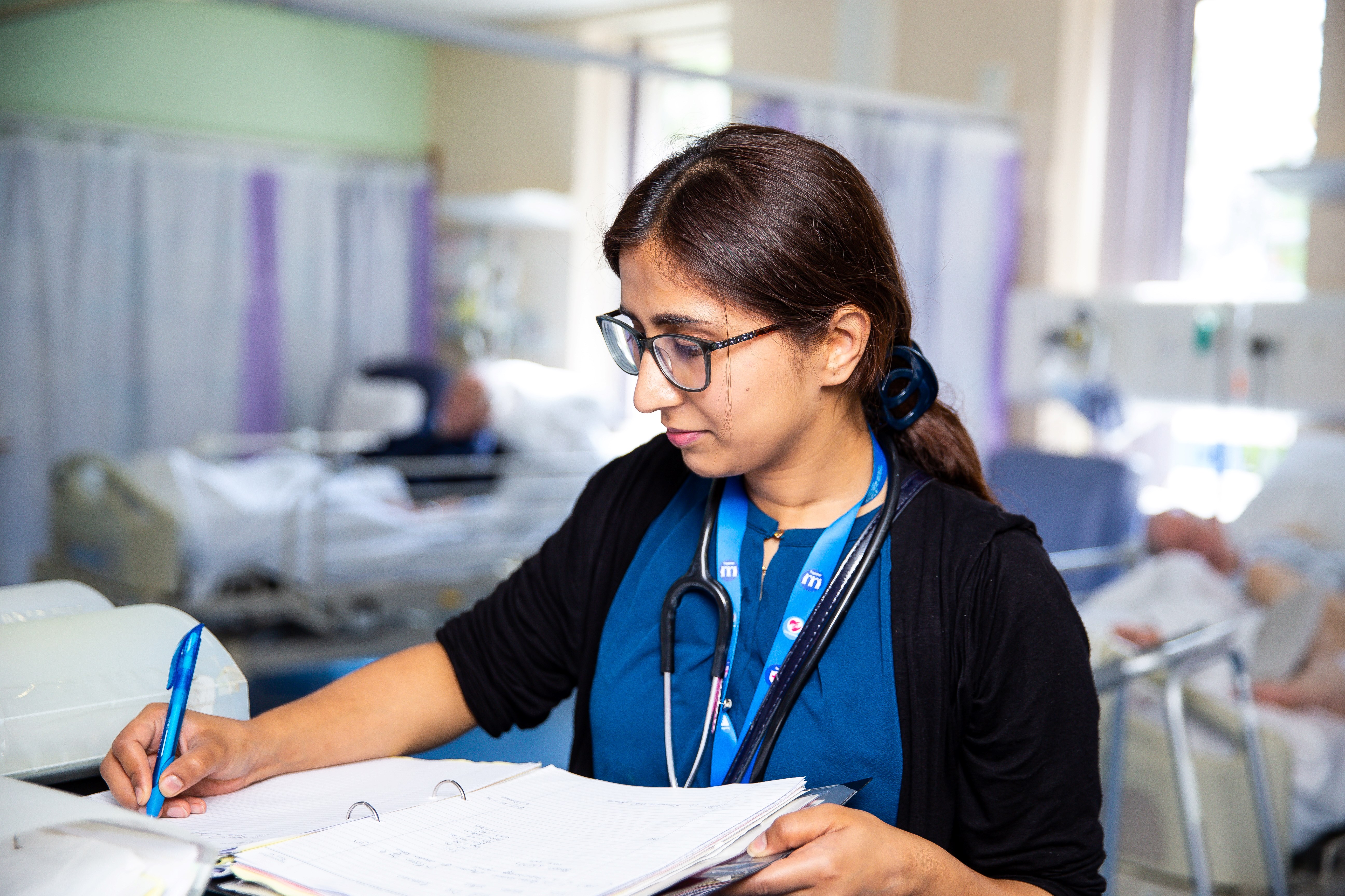 Doctor writing up notes on a ward