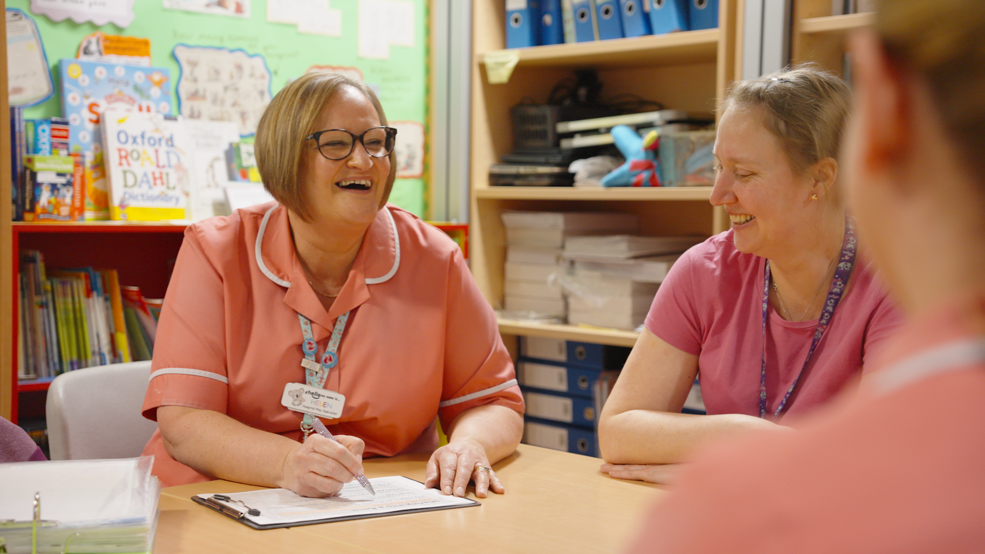 Play specialist meeting with colleagues and laughing